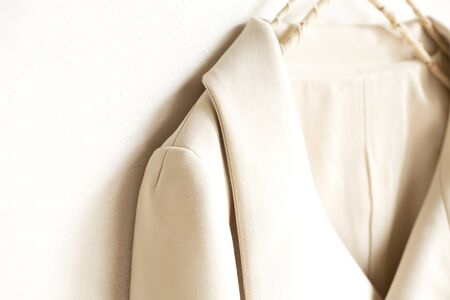 beige or white jacket hanging on clothes hanger on white background.close up.の写真素材