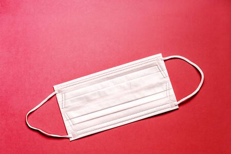 Medical mask, Medical protective mask on red background. Disposable surgical face mask cover the mouth and nose. Healthcare and medical concept.の写真素材