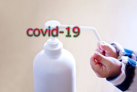 A child sprays her hands with antiseptic from a plastic spray bottle. Hands with a bottle close-up on a blue background and covid-19. Sanitary treatment during an epidemic.の写真素材