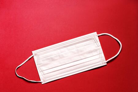 Medical mask, Medical protective mask on red background. Disposable surgical face mask cover the mouth and nose. Healthcare and medical concept.の写真素材
