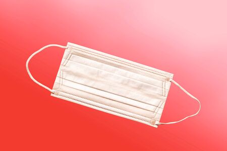 Medical mask, Medical protective mask on red background. Disposable surgical face mask cover the mouth and nose. Healthcare and medical concept.の写真素材