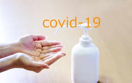 A woman sprays her hands with antiseptic from a plastic spray bottle and and covid-19. Hands with a bottle close-up on a blue background. Sanitary treatment during an epidemic.の写真素材