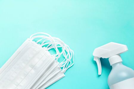 Set of simple white air protection masks on the color surface and Antiseptic solution on blue background and copy space.の写真素材