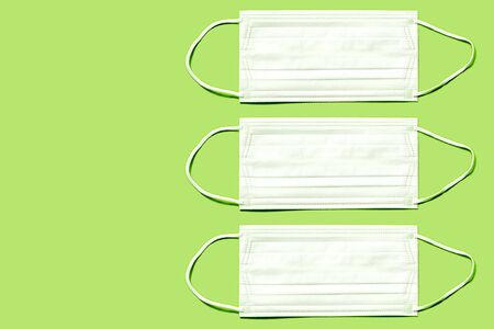 Set of simple white air protection masks on the color surface isolated on yellowish green color background. Colorful Tones,healthcare and medical concept.の写真素材