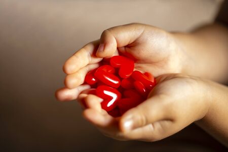 Little child holding red heart, close-up isolated on black gradation and copy space.の写真素材
