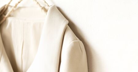 beige or white jacket hanging on clothes hanger on white background.close up.の写真素材