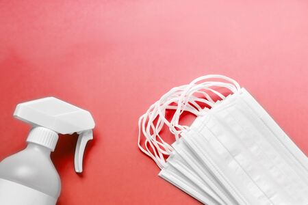 Set of simple white air protection masks on the color surface and Antiseptic solution on red background and copy space.の写真素材