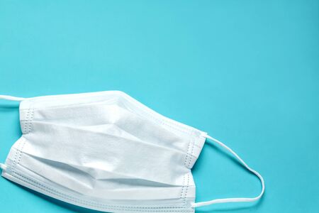 simple white air protection mask on the color surface on blue background. Disposable surgical face mask cover the mouth and nose. Healthcare and medical concept.の写真素材