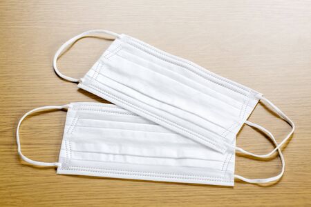 simple white air protection masks on the color surface on wooden background. Disposable surgical face mask cover the mouth and nose. Healthcare and medical concept. two masks.の写真素材