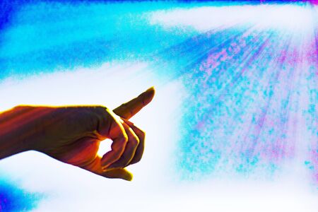 The hand is pointing towards the clouds in the blue sky. Hand symbol points to the light or sunshine.and process a color and copy space.の写真素材