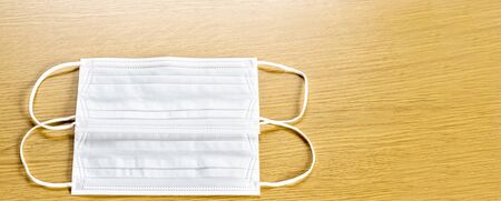 simple white air protection masks on the color surface on wooden background. Disposable surgical face mask cover the mouth and nose. Healthcare and medical concept. two masks.の写真素材