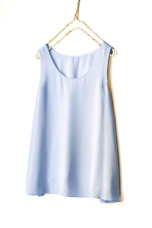 light blue tank top hanging on a hanger in a white wall.Close upの写真素材
