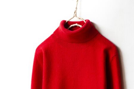 red wool sweater hanging on clothes hanger on white background.close up.の写真素材