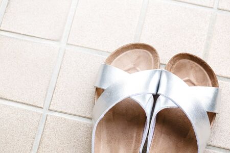 A pair of slipper on skin of silver on beige tiles background and copy space.の写真素材