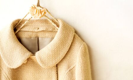 beige wool coat hanging on clothes hanger on white background.Close up.の写真素材