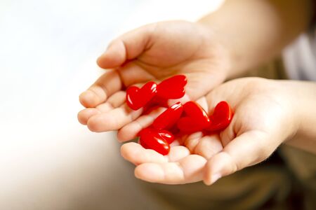Little child holding red hearts, close up isolated on white background. health care, love and family concept, world heart day.の写真素材