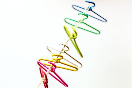 seven multicolored clothes hangers hangs over the chain. Household items. red, pink,yellow,silver,green,light blue,navy. Domestic life,and Top view and copy space.の写真素材