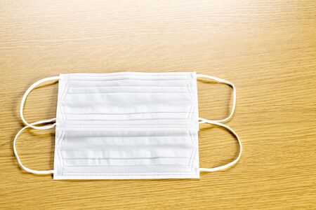 simple white air protection masks on the color surface on wooden background. Disposable surgical face mask cover the mouth and nose. Healthcare and medical concept. two masks.の写真素材