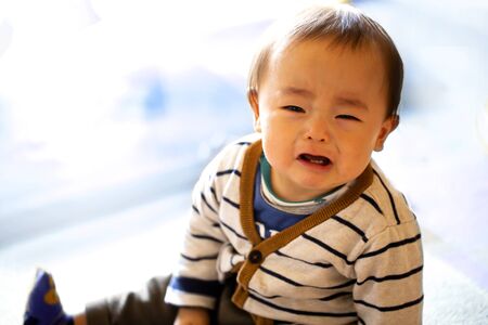 A small child or a baby cries, isolated on white background and copy space.He appeals to mother for sorrow.の写真素材
