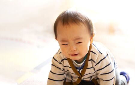 Crying infant baby boy crawling to the camera on the floor and copy space.の写真素材