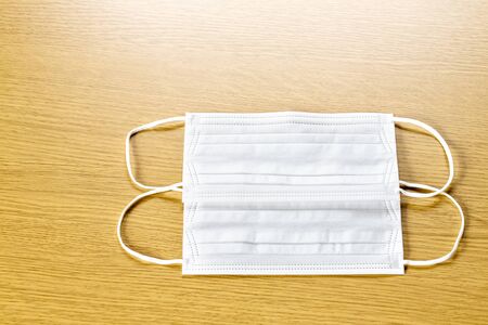 simple white air protection masks on the color surface on wooden background. Disposable surgical face mask cover the mouth and nose. Healthcare and medical concept. two masks.の写真素材