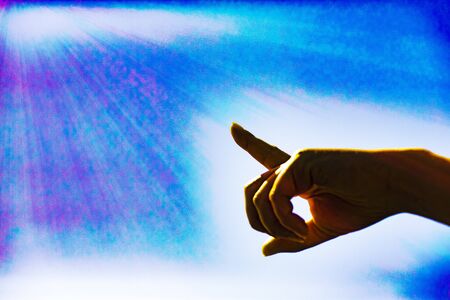 The hand is pointing towards the clouds in the blue sky. Hand symbol points to the light or sunshine.and process a color and copy space.の写真素材