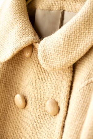 beige wool coat hanging on clothes hanger on white background.Close up.の写真素材