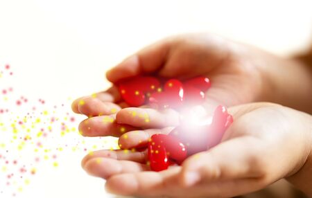 Little child holding red hearts, close up isolated and light, energy with sparkle on white background. health care, love and family concept, world heart day.の写真素材