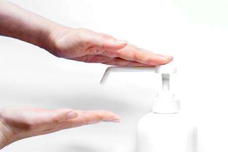 A woman sprays her hand with antiseptic from a plastic spray bottle. Hands with a bottle close-up on a white background. Sanitary treatment during an epidemic.の写真素材