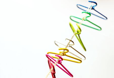 seven multicolored clothes hangers hangs over the chain. Household items. red, pink,yellow,silver,green,light blue,navy. Domestic life,and Top view and copy space.の写真素材