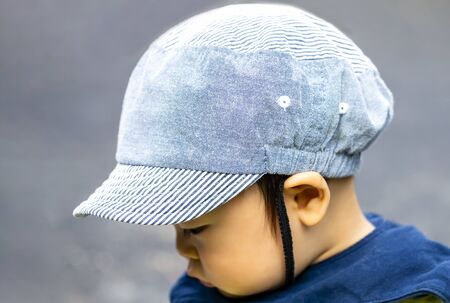 close up of the back of a cute baby boy putting on cap, isolated on gray background and copy space.の写真素材