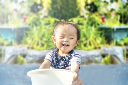 Portrait of happy joyful beautiful little boy isolated on outside background and copy space. boy is dripping wet and plays with water and have a bucket .の写真素材