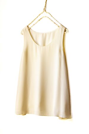 light beige or white tank top hanging on a hanger in a white wall.Close upの写真素材