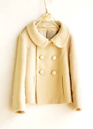 beige wool coat hanging on clothes hanger on white background.Close up.の写真素材