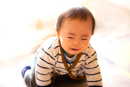 Crying infant baby boy crawling to the camera on the floor and copy space.の写真素材