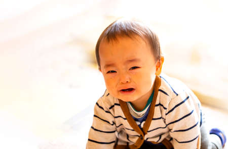 Crying infant baby boy crawling to the camera on the floor and copy space.の写真素材