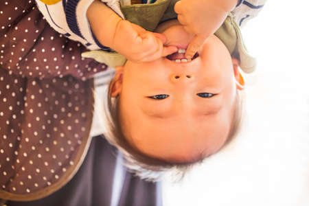 baby boy hanging upside down isolated on white with smile on his face and copy space.の写真素材