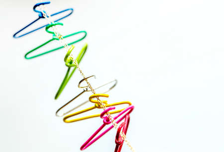 seven multicolored clothes hangers hangs over the chain. Household items. red, pink,yellow,silver,green,light blue,navy. Domestic life,and Top view and copy space.の写真素材