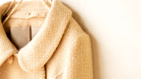 beige wool coat hanging on clothes hanger on white background.Close up.の写真素材