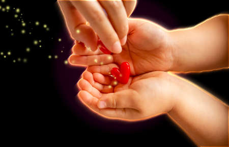 adult and little child holding red hearts, close up isolated and light, energy with sparkle on black background. health care, love and family concept, world heart day.の写真素材