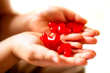 Little child holding red hearts, close up isolated on white background. health care, love and family concept, world heart day.の写真素材