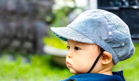 close up of Profile of the cute baby boy putting on cap, isolated on green background and copy space.の写真素材