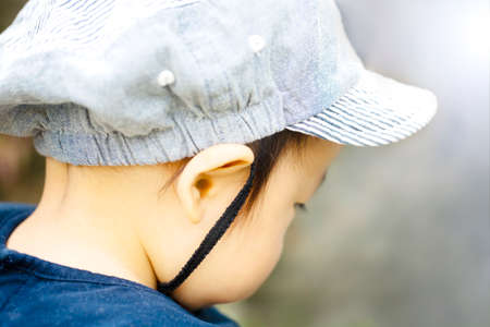 close up of the back of a cute baby boy putting on cap, isolated on gray background and copy space.の写真素材