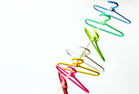 seven multicolored clothes hangers hangs over the chain. Household items. red, pink,yellow,silver,green,light blue,navy. Domestic life,and Top view and copy space.の写真素材