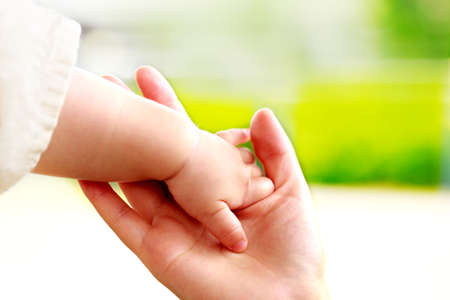 Family scene , close up parent and baby holding hands together and green and whier background with copy space.の写真素材