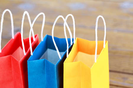 Colorful paper bags on the table on a wooden backgrounds and close up. red, blue, yellow.の写真素材