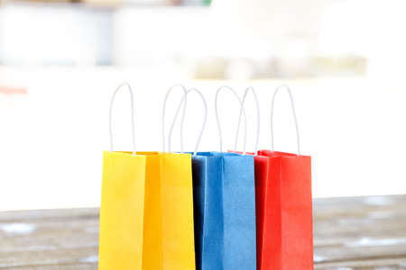 Colorful paper bags on the table on a light blurred and wooden backgrounds and close up. red, blue, yellow.の写真素材