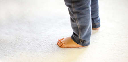 Child walking on carpet background in house. Child foot with jeans pants . close up and copy space.の写真素材