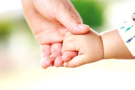 Family scene , close up parent and baby holding hands together and green and whier background with copy space.の写真素材
