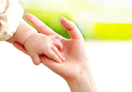 Family scene , close up parent and baby holding hands together and green and whier background with copy space.の写真素材